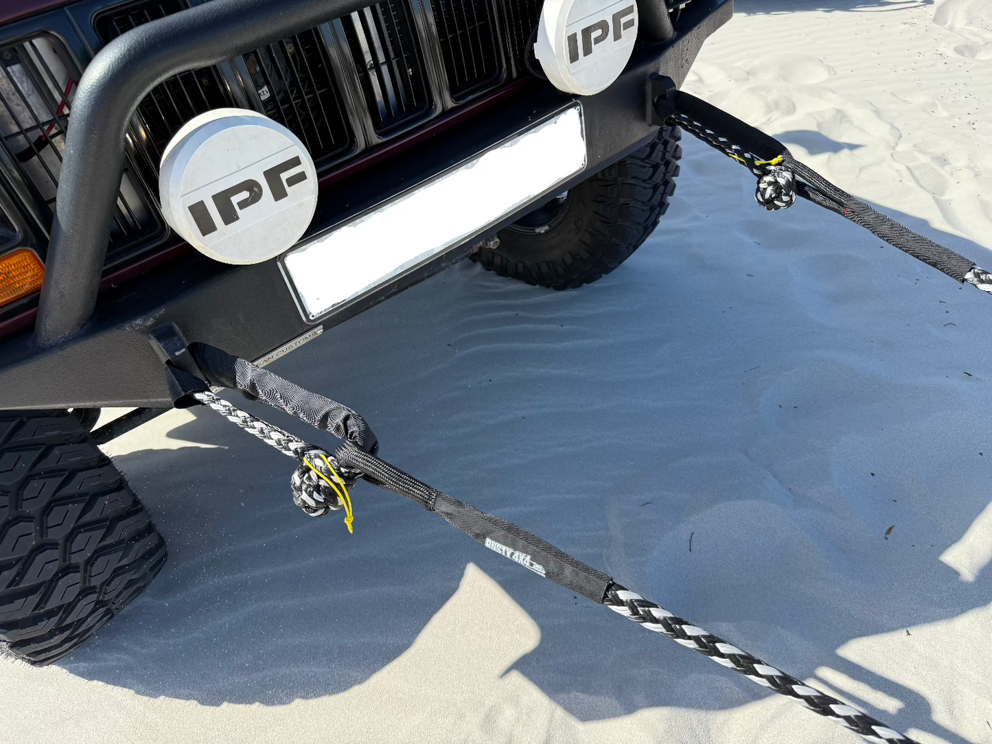 Soft shackle braided rope with black sleeve and yellow tie cord, attached to tow bar