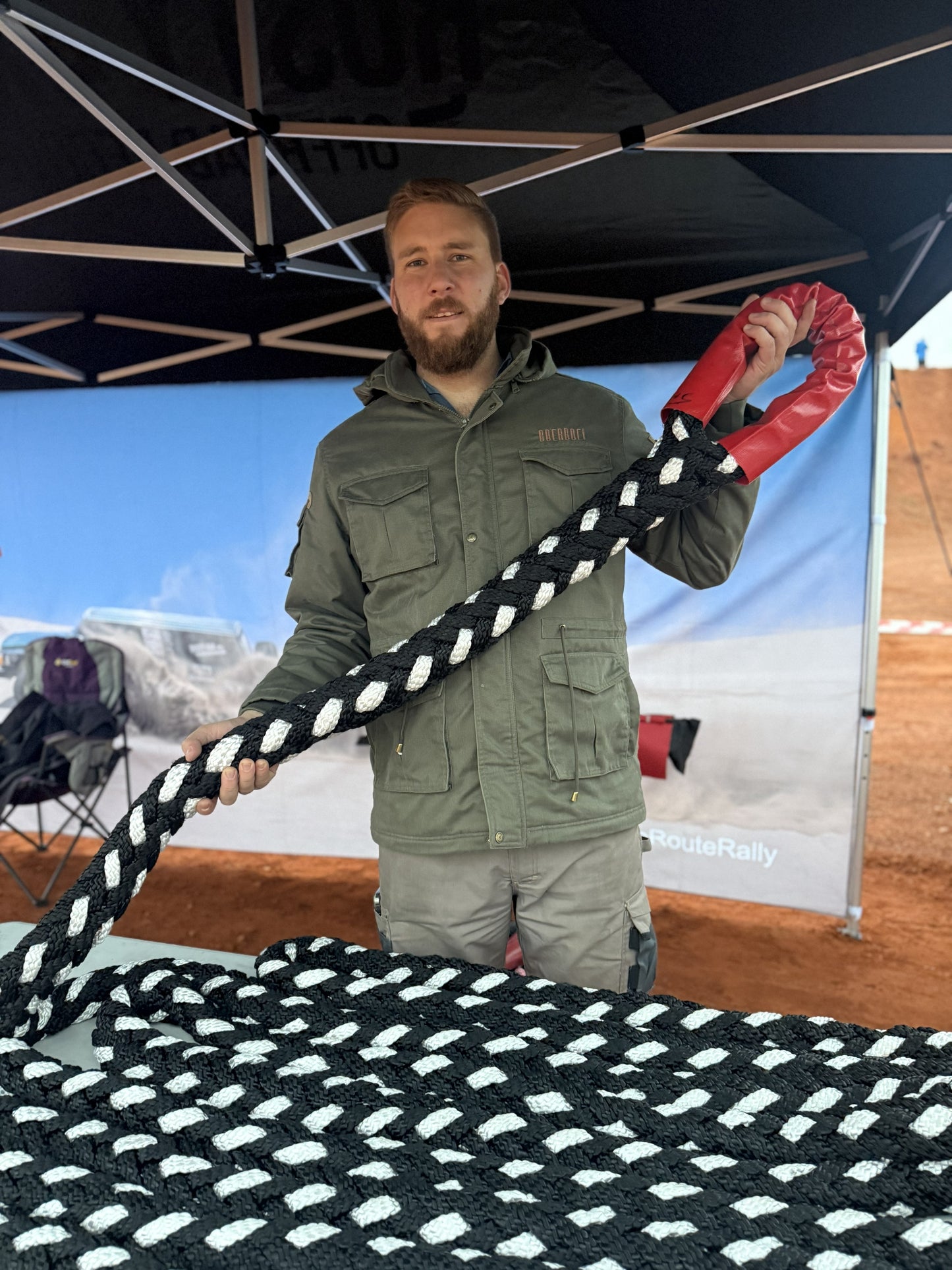 Black-and-white braided kinetic recovery rope held by person wearing green jacket