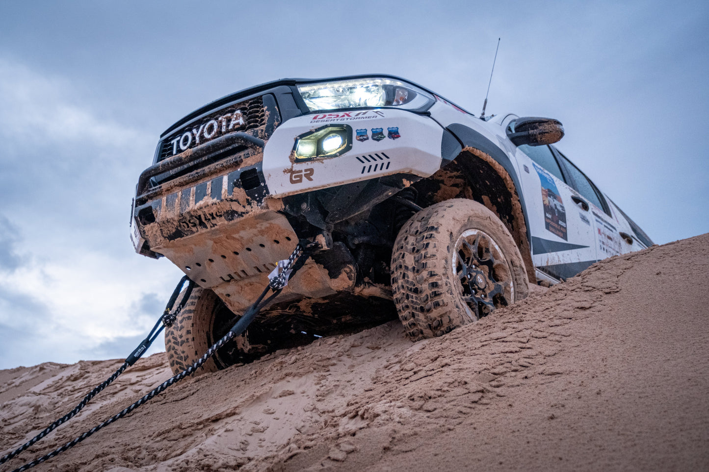 Kinetic recovery rope attached to front of an off-road vehicle, pulling on sand