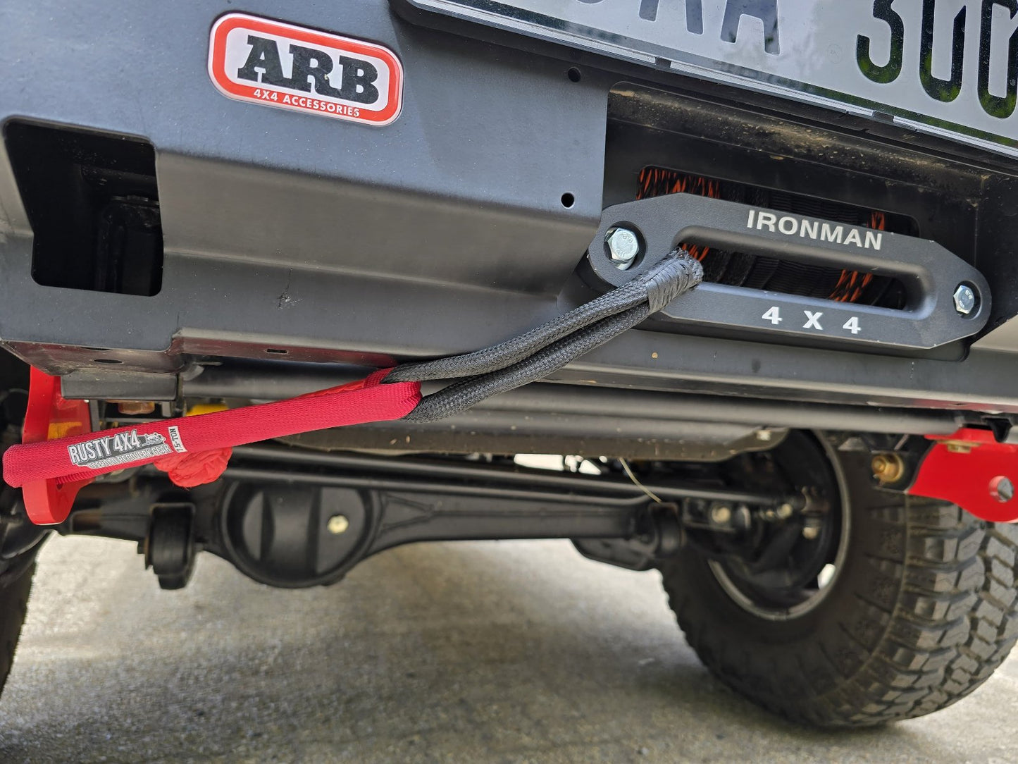 Winch line and fairlead on vehicle bumper with red strap and gray mounting plate