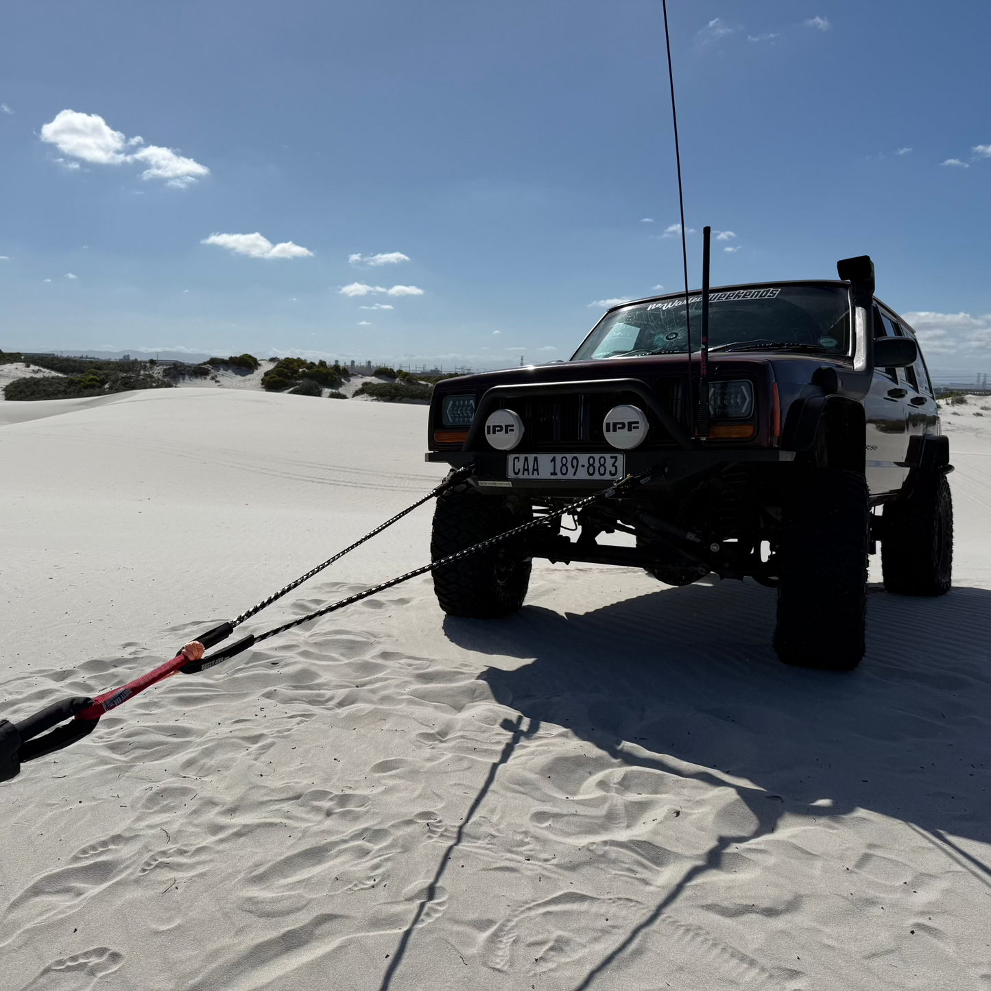 Braided recovery rope bridle laid on sand with visible metal ends and ties