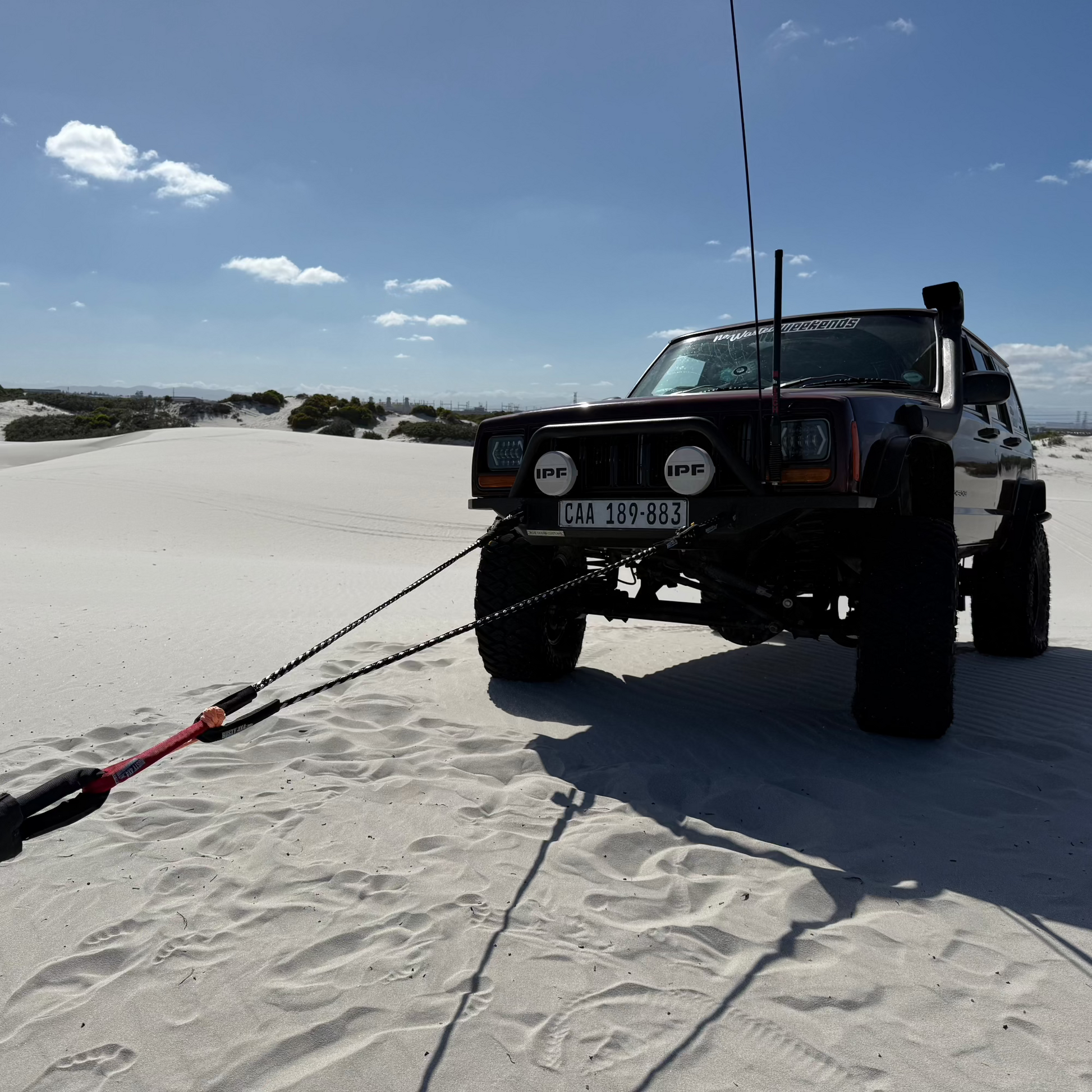 Braided recovery rope bridle laid on sand with visible metal ends and ties