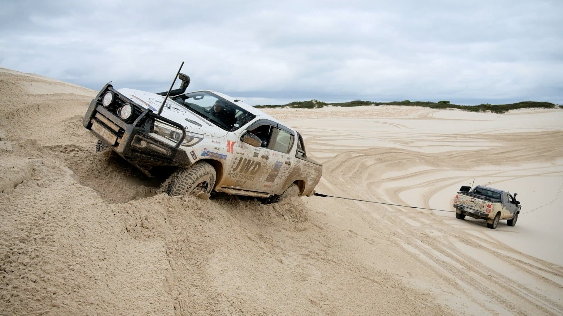 Kinetic recovery rope in action as an off-road vehicle drags it through sand