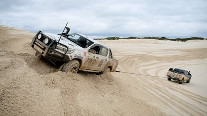 Kinetic recovery rope in action as an off-road vehicle drags it through sand