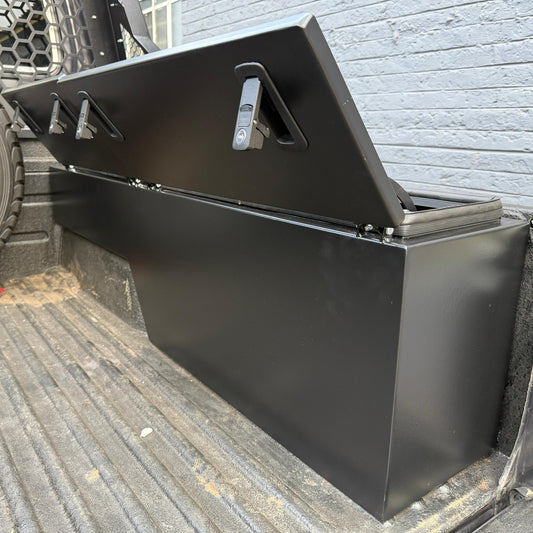 Black metal tool box on a truck bed with a brick wall background