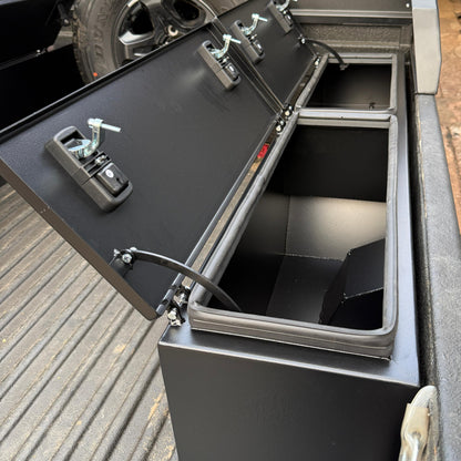 Truck bed with a storage compartment and tire in the background