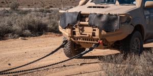 Kinetic recovery rope trailing from a vehicle bumper on sandy terrain