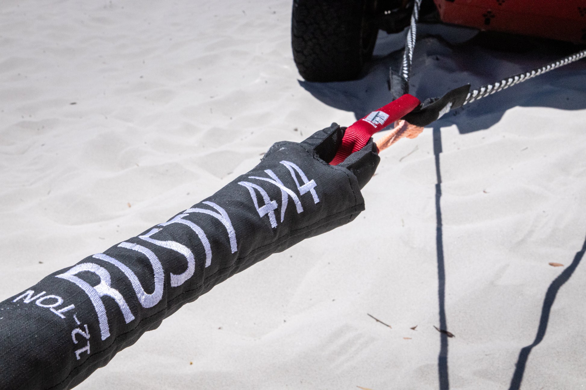 Black-and-white recovery strap with red tag and braided rope connected to ends