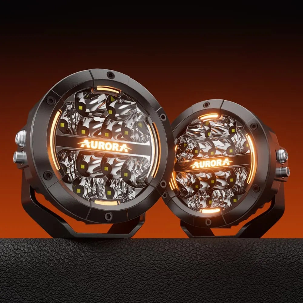 Aurora 5-inch driving light with amber DRL — white and amber lit pair on an orange background